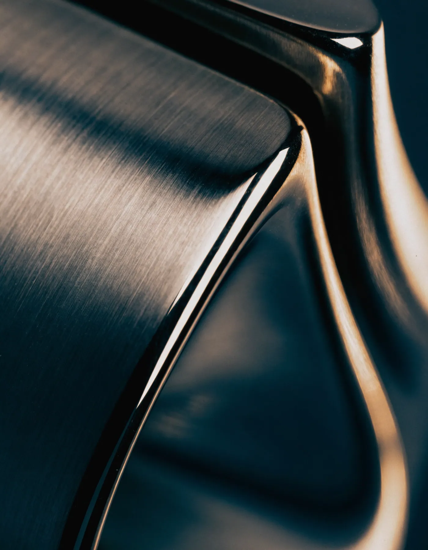 Polished metal detail under directional light on a dark ground.